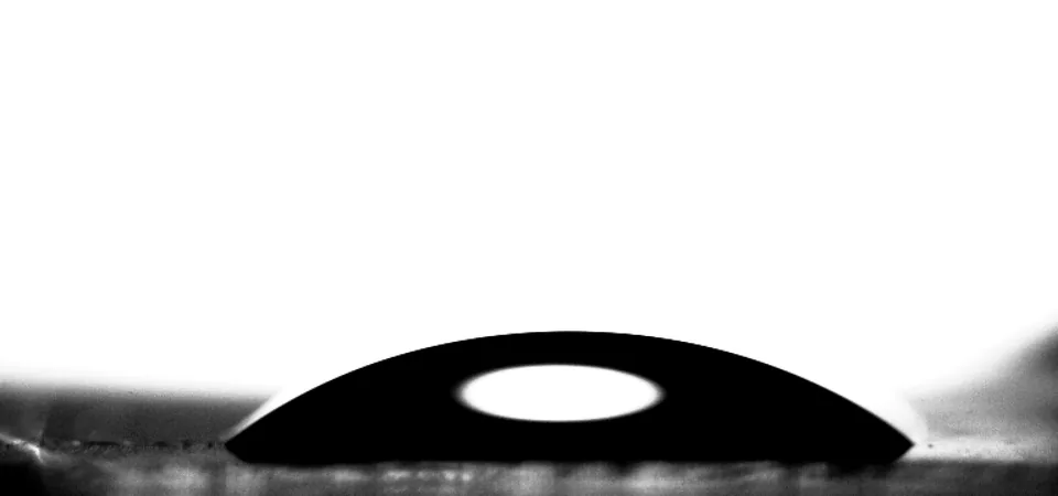 Water drop on glass at 14.0 °C, spread into a low cap.